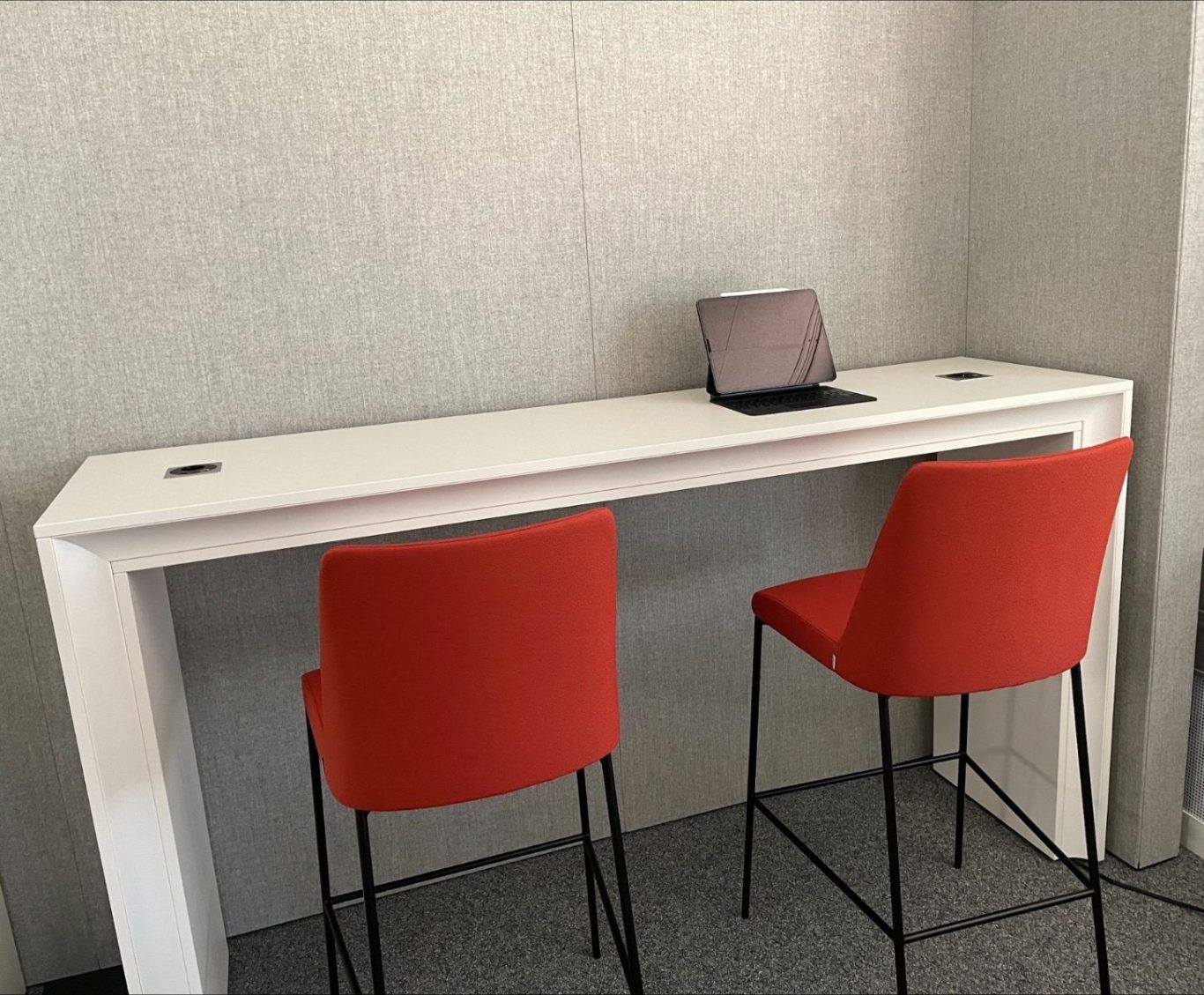 Loungeecke mit terrakotta- und rosafarbenen Sofas, Sesseln und runden Hockern vor einer Wand mit dekorativer Unterwassermotiv-Tapete