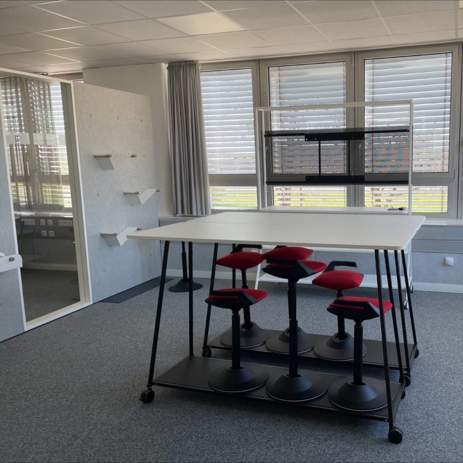 Zwei verglaste Fokusräume nebeneinander im Büro, links mit blauem und rechts mit gelbem geometrischem Wandmuster gestaltet